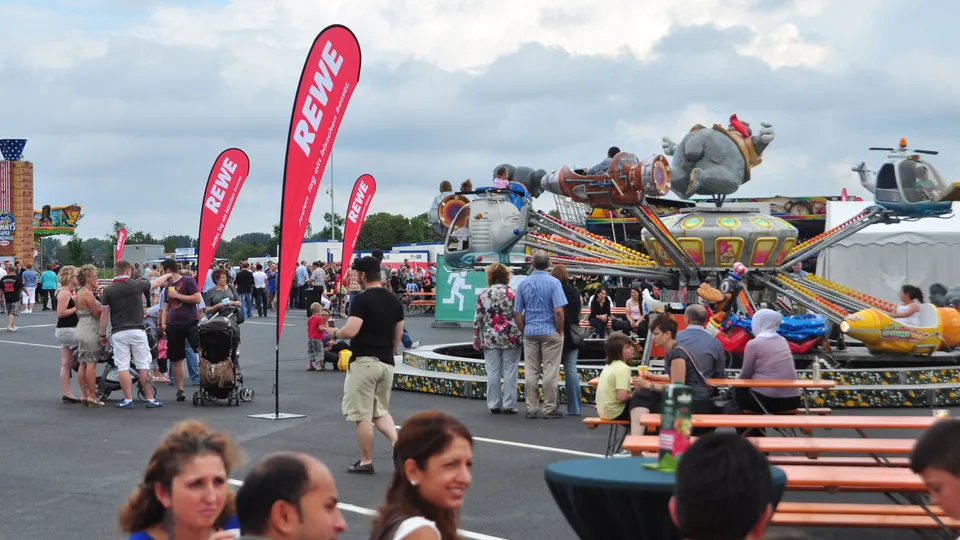 Das Sommerfest von Rewe mit einem Karussell auf einem Platz.