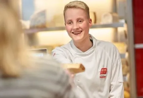Rewe Mitarbeitende servieren Kaese an der Frischetheke. 