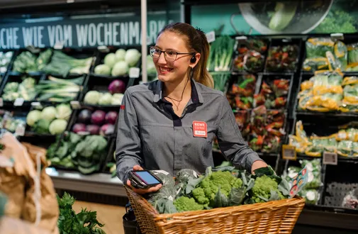 Eine duale REWE Studentin im Handel raeumt Obst ein