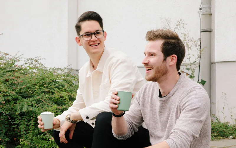 Zwei REWE Studenten trinken gemeinsam eine Getraenk 
