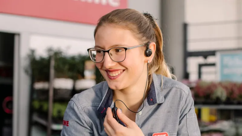 Eine REWE Mitarbeiterin haelt Blumen in der Hand