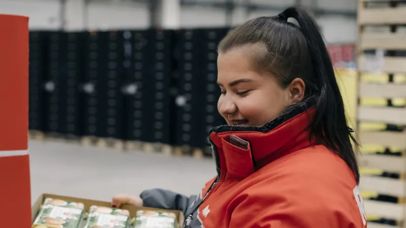 EinE REWE Mitarbeiterin haelt Kartoffeln in einer Kiste in den Haenden