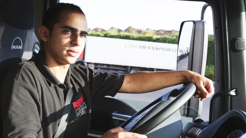 Ein REWE Mitarbeiter sitzt im Fahrerhaus eines LKW