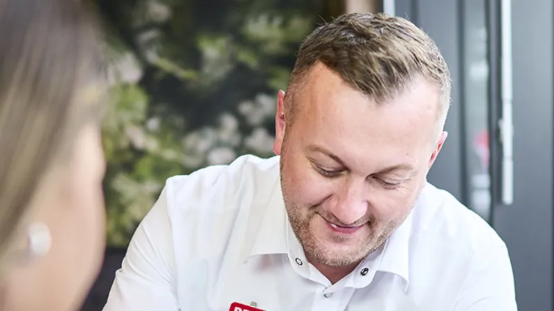 Ein REWE Mitarbeiter zeigt Produkte auf einem Handy