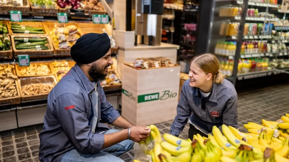 Zwei Mitarbeitende arbeiten gemeinsam an der Anrichtung der Bananen.