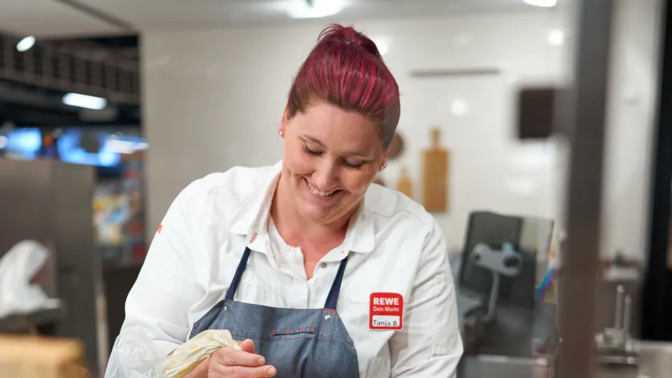 Eine REWE Mitarbeiterin bereitet eine Torte vor