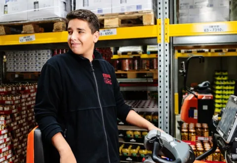 Eine Rewe Mitarbeiterin arbeitet im Logistik Lager. 