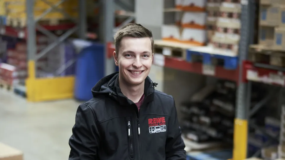 Der Kommissionierer Florian Greven fährt mit einem Hubwagen durch das Lager.