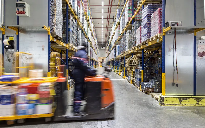 Ein Mitarbeiter transportiert Paletten im Logistik Lager.