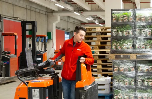 Ein REWE Auszubildender zum Fachlagerist sortiert Ware im Lager