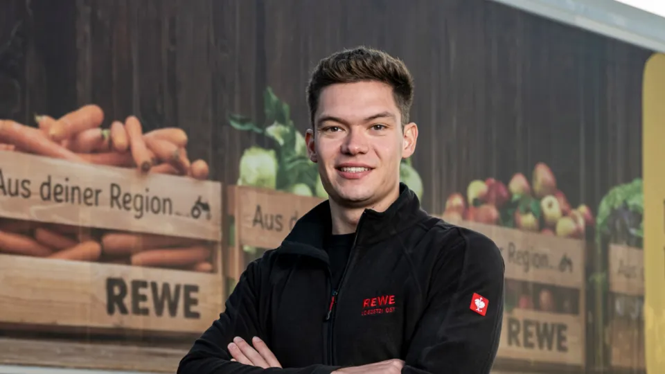 Ein REWE Mitarbeiter vor einem REWE LWK